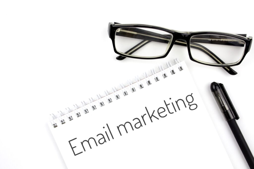 Image of glasses placed next to a notebook with the words 'email marketing' written on it. This image is used to illustrate an email marketing blog