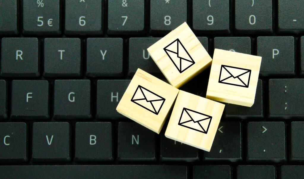Image of a black keyboard with four wooden keys, each imprinted with a letter. This image is used for the purpose of illustrating an email marketing blog related to administration.